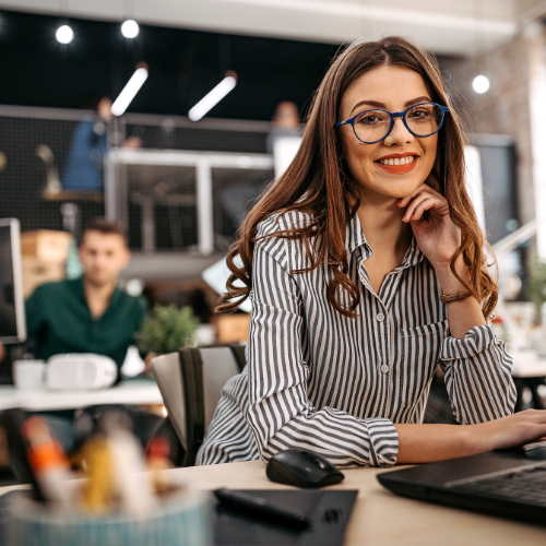 A woman in an office smiling at her desk